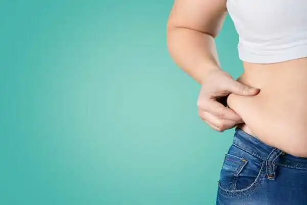 Image of woman pinching her love handles to show weight gain Benson